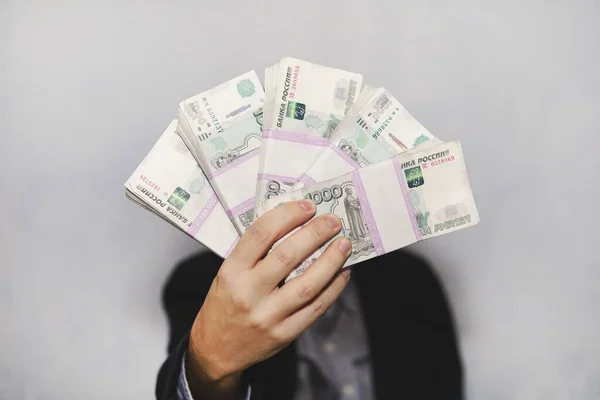 Montón de billetes de cinco mil rublos rusos en mano de hombre sobre fondo azul. Paquete de billetes de 1000 rublos de la Federación Rusa . —  Fotos de Stock