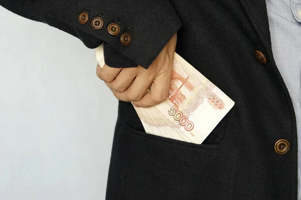 Brodaty biznesmen w garniturze zdejmuje rosyjskie ruble do kieszeni garnituru. Temat finansowy. Facet wkładał banknoty do kieszeni. Wynagrodzenie. — Zdjęcie stockowe