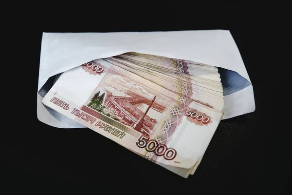 Soldi in busta bianca. Corruzione rublo in una busta su sfondo nero . — Foto Stock