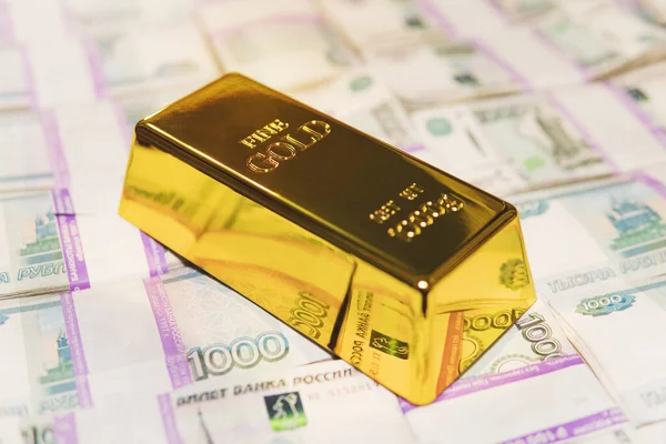 A kilogram gold bar is on the banknotes of 1000 rubles. Close up of banknotes with pure gold bar for business, investment or financial