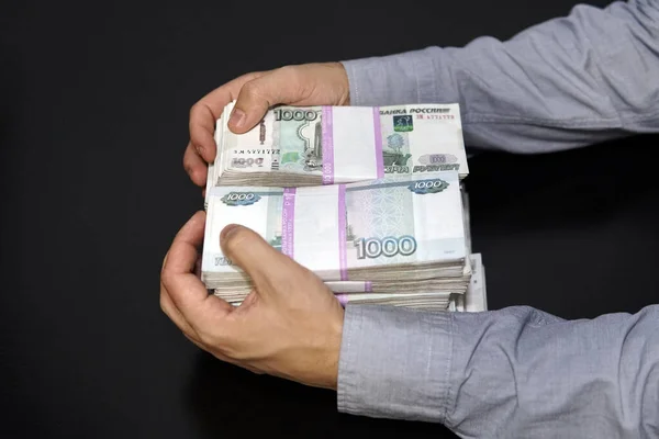 Las manos masculinas agarraron una gran suma de dinero. Hombre de negocios anónimo extendiendo la mano para agarrar dinero, moneda de rublo ruso, en cuarto oscuro —  Fotos de Stock