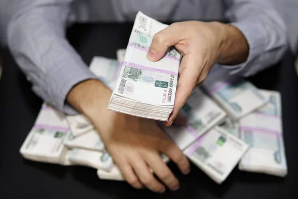 Las manos de los hombres buscan un fajo de dinero. Un millón de rublos en la mesa negra. El concepto de riqueza, éxito, codicia y corrupción, lujuria por el dinero —  Fotos de Stock