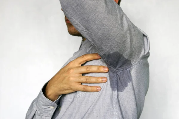 Mancha mojada en mi camisa azul de sudor. hombre transpirando olor desagradable sobre un fondo azul . —  Fotos de Stock