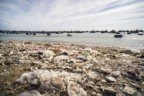 Vista em uma praia de areia perto de vila de pescadores com um monte de lixo. Poluição de um litoral. Mui Ne — Fotografia de Stock