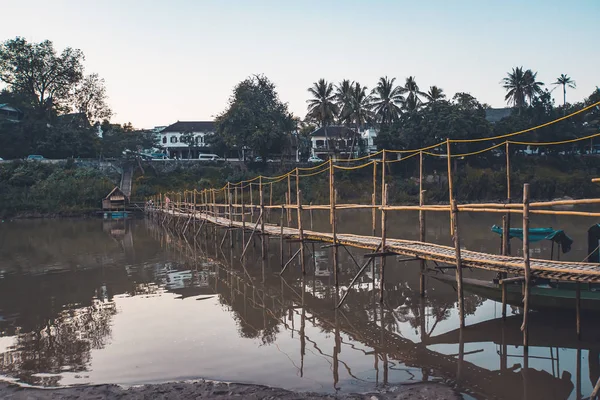 Luang Prabang, Laos - Bamboo bridge across river with the tourists on them. Green grass on the shore — Stockfoto