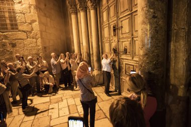 JERUSALEM, ISRAEL. 24 October 2018: tourists take pictures on smartphones ritual of closing doors of the Church of Holy Sepulchre. Muslim key holder locks the doors clipart