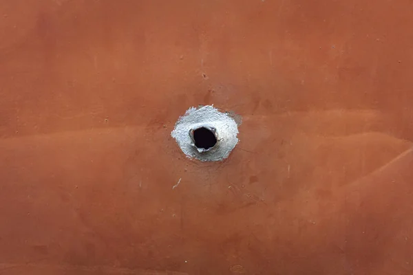 external bullet hole. hole with black center in the iron plate