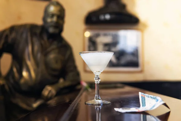 Glas av Daiquiri cocktail och staty av den amerikanske författaren Ernest Hemingway i baren El Floridita i Havanna — Stockfoto