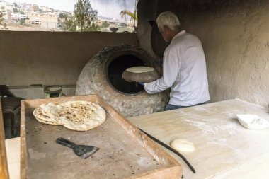 Bir erkek şef kalp şeklinde ekmek yapar. Geleneksel Arap ekmeği, Ürdün 'de kömürde pişiyor. Jerash..