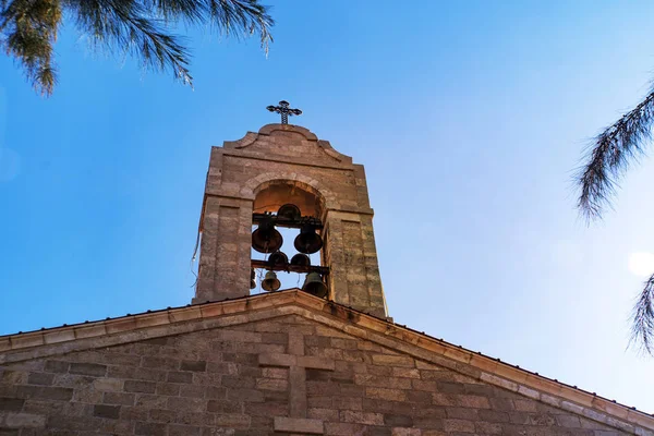 Kirchturm auf dem Dach der christlich-orthodoxen byzantinischen griechischen Kirche. große Bronzeglocke und ein großes weißes Kreuz, Hintergrundansicht des blauen bewölkten Himmels — Stockfoto