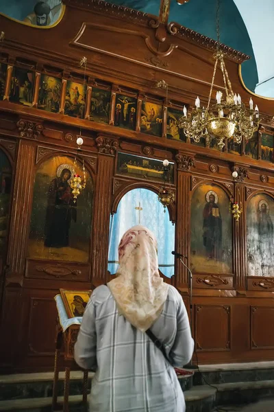 Stará žena stojí v ortodoxní církvi a modlí se na ikoně. Pohled zezadu.. — Stock fotografie
