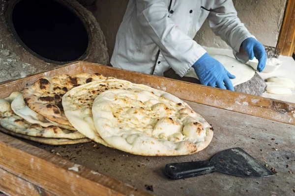 Мужчина-повар делает хлеб в форме сердца. Традиционный арабский хлеб, выпекаемый на угле в тандыре Иордании. Джераш . — стоковое фото