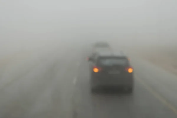 Poor visibility on the road. Fog early in the morning on the highway. slow-moving cars in heavy smoke from forest fires. Dangerous traffic. Bad weather. Slippery asphalt. driver's eyesight is poor — 스톡 사진