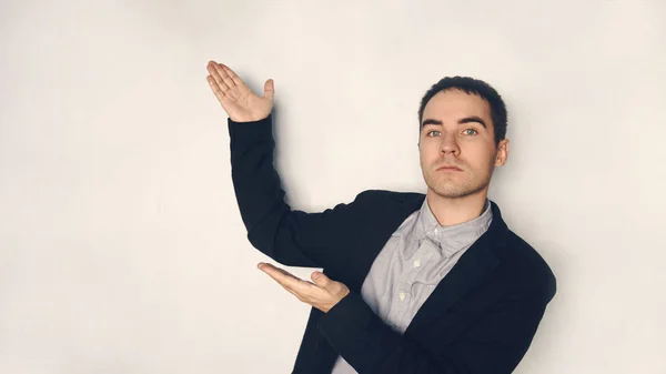 Homme d'affaires présentant la présentation. Je pointe mes paumes vers l'espace vide. Beau jeune homme en costume présentant quelque chose — Photo