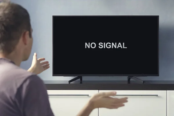 デジタルテレビの信号が悪い テレビ画面には表示されません 男はテレビが故障することについて動揺している — ストック写真