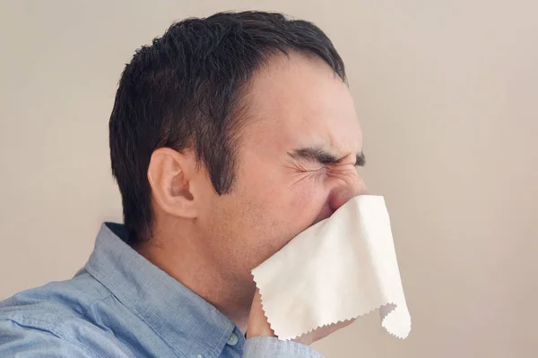 businessman blows his nose in a rag. Young man sneezes into tissue. guy is sick, has a cold or allergic reaction. Coronavirus, epidemic 2020, illness concept.