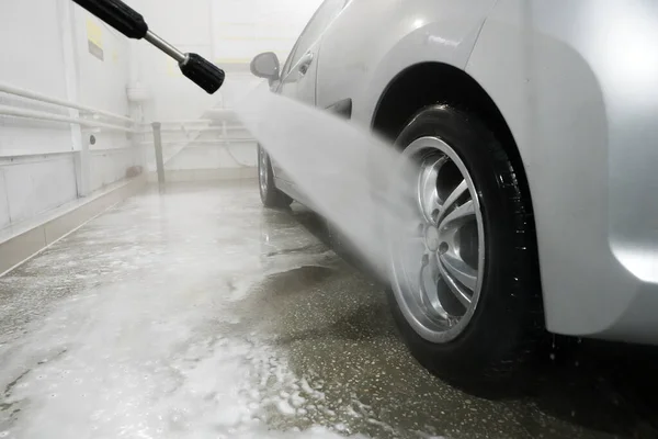 Man cleaning vehicle with high pressure water spray or jet. Car wash details. wash the wheels with water. washing the rear wheel of a car
