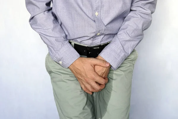 Urinary incontinence concept. Wet person. Blue background. adult man holds hands the groin area and trousers wet from urine. Health problem. Medical concept. — Stock Image Urinary Incontinence Concept Wet Person Blue Background Adult Man Holds Royalty Free Stock Images