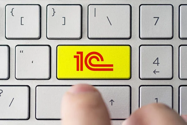 Erkek, klavyedeki 1C logosuna basıyor. 1C, bilgisayar programları ve veritabanlarının dağıtımı, desteklenmesi ve geliştirilmesi konusunda uzman bir Rus şirketidir.