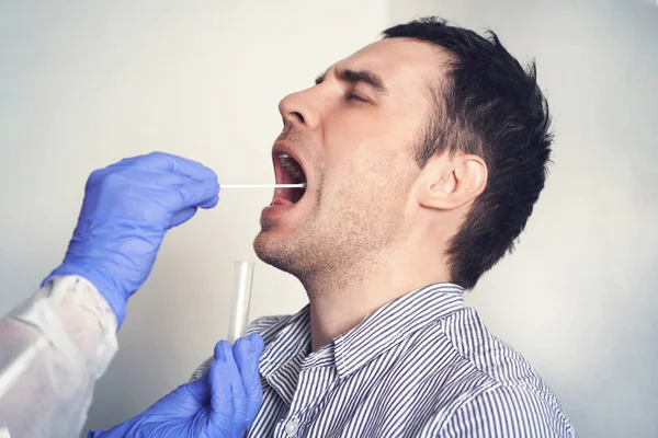 DNA testi. Doktor, erkek hasta için Coronavirus covid 19 testi yapıyor. Bir adamdan tükürük örneği alıyorum. Laboratuvarda araştırma yapmak için boğazından mukus topladım..
