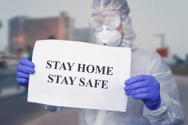 doctor in a protective suit at wear medical masks, holding paper with text STAY HOME STAY SAFE. stay at home in self-isolation policy campaign to control COVID-19 Coronavirus outbreak situation. warn