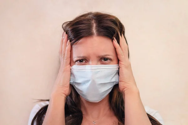 patient woman using the medical, face mask, protective mask, medical mask coughing. Headache.Virus protection concept. The fear of a pandemic coronavirus infection. sick girl holds her head.