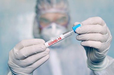 COVID-19. Coronavirus swab sample COVID-19. swab coronavirus test. Epidemic outbreak. a man in a chemical protection suit holds a test tube for analysis. clipart