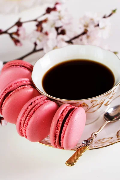 Macaroons coloridos e uma xícara de café na mesa de madeira . — Fotografia de Stock