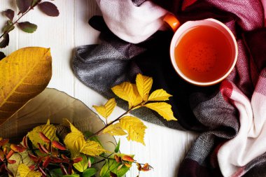 Beyaz ahşap bir masa üzerinde bardak çay ve sonbahar yaprakları 