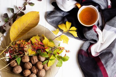 Beyaz ahşap bir masa üzerinde bardak çay ve sonbahar yaprakları 
