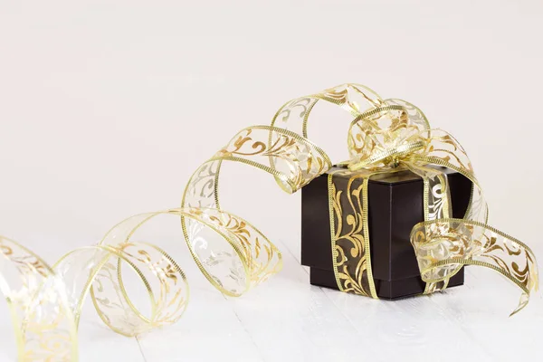 Geschenkbox mit goldenem Band auf weiß lackiertem Holzhintergrund. — Stockfoto