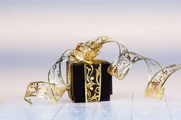 Geschenkbox mit goldenem Band auf weiß lackiertem Holzhintergrund. — Stockfoto