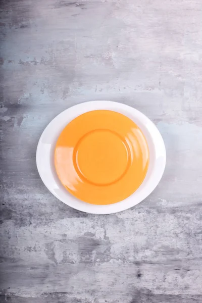 Empty yellow and white plate above over gray texture background. — Stock Photo, Image