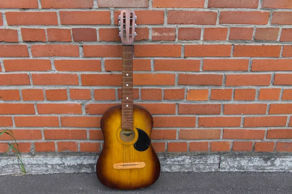 Kırmızı tuğla duvara dinlenme akustik gitar