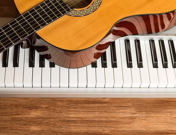 Teclado de guitarra y piano sobre fondo de madera — Foto de Stock