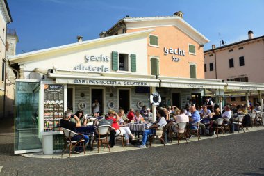 Bardolino Italya 'da bir restoranda yemek yiyen insanlar. Bardolino' daki Yat restoranı müşterilerle dolu..