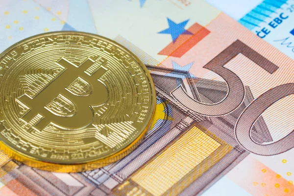 Moneda metálica de oro bitcoin sobre billetes en euros — Foto de Stock