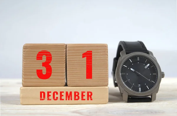 31 december, calendar on wooden blocks with wrist watch — Stock Photo, Image