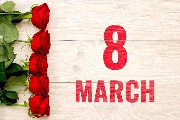 8 Μαρτίου στο ξύλινο τραπέζι διακοσμημένο με κόκκινα τριαντάφυλλα — Φωτογραφία Αρχείου