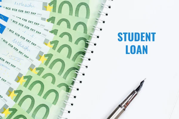 Student loan concept. Notepad, pen, 100 euro banknotes.