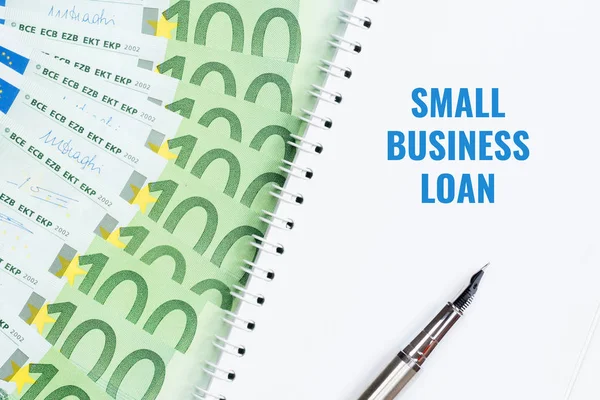 Small business loan concept. Notepad, pen, 100 euro banknotes.