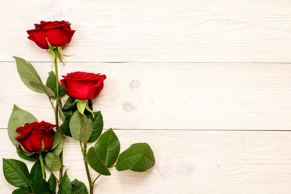 3 rosas vermelhas na tabela envelhecida branca — Fotografia de Stock