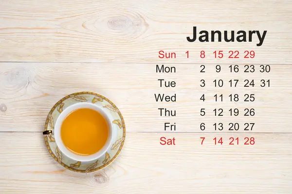 Calendário de janeiro, mesa branca com xícara de chá — Fotografia de Stock