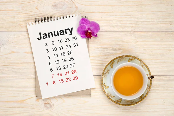 Calendário de janeiro, mesa branca com xícara de chá e flowe orquídea — Fotografia de Stock