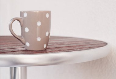 Yuvarlak ahşap masa üzerinde gri puantiyeli Kupası