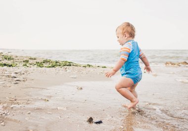Bir yıl yaşlı erkek çocuk sahilde oynuyor