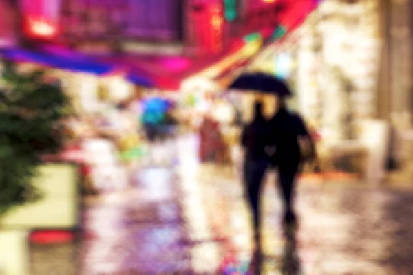 Silhuetas de casal andando sob a chuva na cidade noturna — Fotografia de Stock