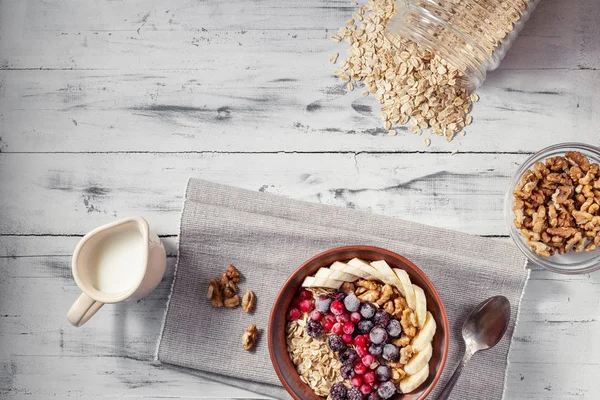 Oatmeal in bowl with berries, bananas and walnuts — Stock Photo, Image