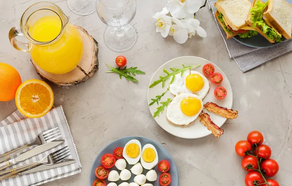 Frühstückstisch mit Spiegeleiern, Speck, Kirschtomaten, Sandwiches — Stockfoto