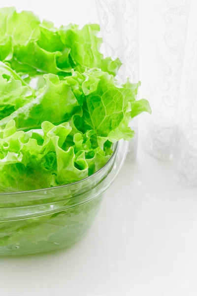 Hojas de lechuga fresca empapadas en un tazón de plástico transparente —  Fotos de Stock